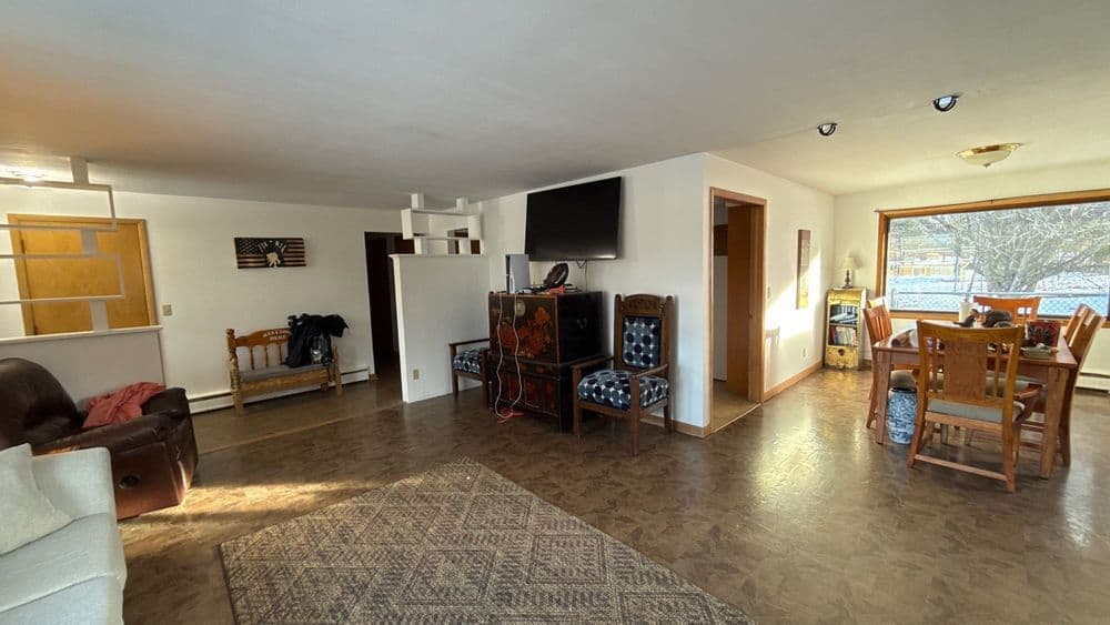 Spacious living room with dining area, hardwood floors, and natural light from large windows.