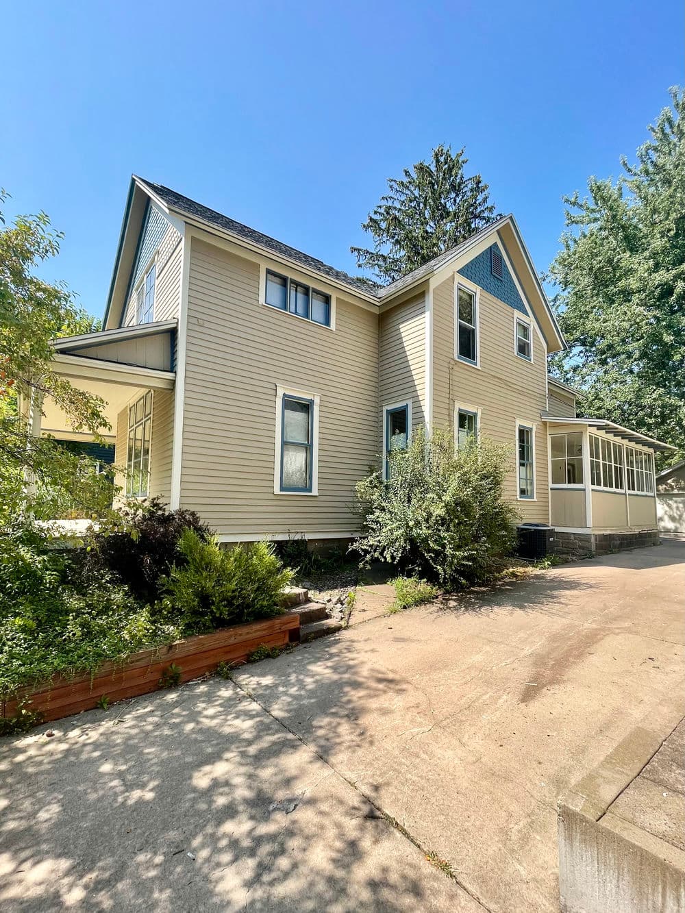 Two-story vintage home with landscaped yard and clear blue sky in the background.